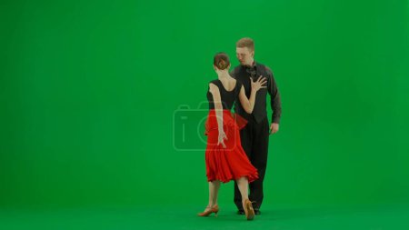Téléchargez les photos : Un élégant duo de danse de salon exécute une routine dynamique capturée sur un fond vert vif. Cette image est parfaite pour les projets qui nécessitent une composition chromatique clé, offrant une polyvalence - en image libre de droit