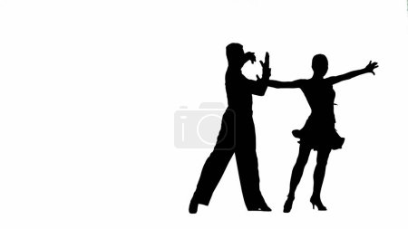 Foto de Esta llamativa imagen captura la silueta de una pareja de bailarines de salón en una pose dinámica, mostrando la elegancia y la pasión de la danza. El hombre y la mujer son representados en medio de la danza paso, sus cuerpos - Imagen libre de derechos