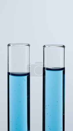 Foto de Dos tubos de ensayo de vidrio sobre fondo blanco. Los tubos de ensayo están llenos de líquido azul. Concepto de medicina, investigación bioquímica. Primer plano - Imagen libre de derechos