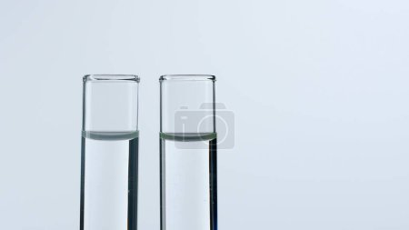 Foto de Dos tubos de ensayo de vidrio sobre fondo blanco. Los tubos de ensayo están llenos de líquido transparente. Concepto de medicina, investigación bioquímica. Primer plano - Imagen libre de derechos