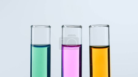 Photo for Concept of science and biotechnology. Laboratory glassware on white background. Test tubes filled with pink, green and yellow liquid. Close up - Royalty Free Image