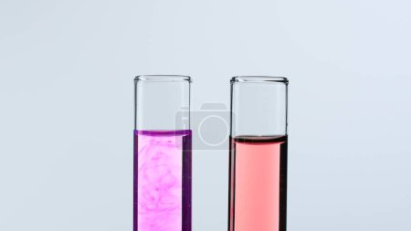 Foto de Concepto de ciencia y biotecnología. Vidrio de laboratorio sobre fondo blanco. Tubos de ensayo llenos de líquido rosa y rojo. De cerca. - Imagen libre de derechos