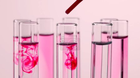 Photo for Science and biotechnology creative concept. Close up laboratory glassware on pink background. Test tubes with transparent and pink liquid. Person adds pink fluid with pipette in test tubes - Royalty Free Image