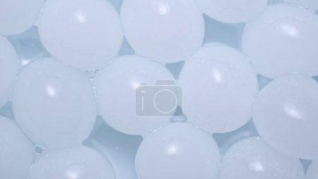 Téléchargez les photos : Beaucoup de sphères d'hydrogel blanc. Les sphères rondes brillantes de gel scintillent sur le fond blanc du studio. Concept créatif de publicité cosmétique dans l'industrie de la beauté - en image libre de droit