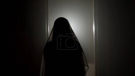 Photo for Horror movie and poltergeist creative advertisement concept. Portrait of ghost female in the house. Woman in white dress with veil covering her face in the place with lightning. - Royalty Free Image