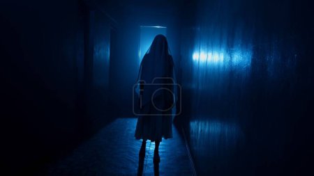 Foto de Película de terror y concepto de publicidad creativa poltergeist. Retrato de una mujer fantasma en la casa. Mujer en vestido blanco con velo cubriendo su cara caminando en la habitación con un rayo azul. - Imagen libre de derechos