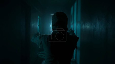 Horror movie and poltergeist creative advertisement concept. Portrait of ghost person in the house. Mummy covered in white cloth ribbons walking in the corridor with blue flashing lightning.