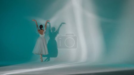 Foto de Concepto clásico y moderno de publicidad creativa de ballet. Retrato de mujer sobre fondo verde en estudio de luz blanca. Joven bailarina en tul blanco bailando salto elemento de coreografía. - Imagen libre de derechos
