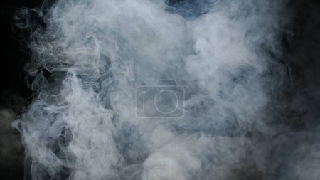 Foto de Imagen de humo de nube blanca flotando en el aire sobre un fondo negro. La textura del humo y el contraste con el fondo negro dan profundidad y misterio a la imagen - Imagen libre de derechos