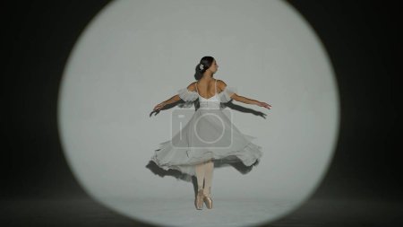 Téléchargez les photos : Ballet classique et moderne concept de publicité créative. Portrait de femme sur fond blanc en studio sous les feux des projecteurs. Élégante ballerine en tulle blanc dansant montrant un élément fendu élevé. - en image libre de droit