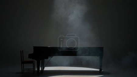 Foto de Concepto de publicidad creativa de música e instrumentos. Primer plano de piano clásico. Hermoso piano negro de pie en el estudio sobre fondo blanco, con poca luz y humo sobre él. - Imagen libre de derechos