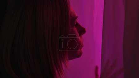 Foto de Retrato de perfil de una mujer preocupada en una ventana de cerca. Mujer mirando luces policiales fuera de la ventana - Imagen libre de derechos
