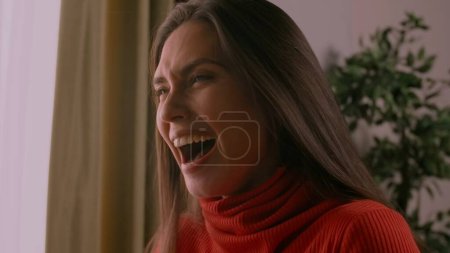 Photo for Human emotions and positivity creative advertisement concept. Portrait of beautiful female model in good mood. Brunette woman in red sweater sitting in the studio and laughing with mouth open. - Royalty Free Image