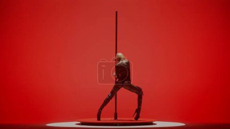 Photo for Modern dance style and choreography creative concept. Portrait of young female dancer in the studio. Professional pole dancer girl dancing on pylon, showing modern pole dance, red neon background. - Royalty Free Image
