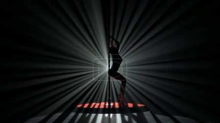 Photo for Modern dance style and choreography creative concept. Portrait of young female dancer in the studio. Professional pole dancer girl silhouette dancing modern pole dance against bright spotlight. - Royalty Free Image