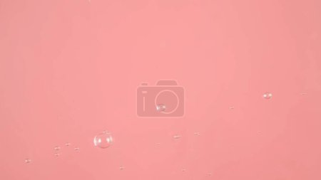 Foto de La superficie del agua sobre un fondo rosa. Las burbujas son visibles en el agua - Imagen libre de derechos