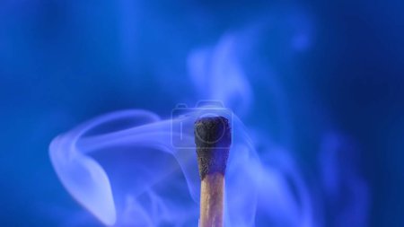 Photo for Macro shot of a black charred match and clouds of white smoke. Burned extinguished wooden match on dark studio background - Royalty Free Image