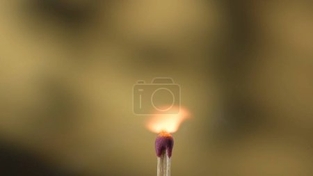 Foto de Macro toma de un partido en llamas contra un fondo de estudio amarillo. La llama de la cerilla encendida ilumina el espacio oscuro. El fósforo ardiente está envuelto en una llama naranja - Imagen libre de derechos