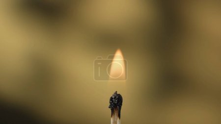 Foto de Macro toma de un partido en llamas contra un fondo de estudio amarillo. La llama de la cerilla encendida ilumina el espacio oscuro. El fósforo ardiente está envuelto en una llama naranja - Imagen libre de derechos