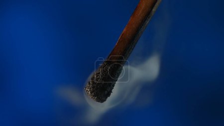 Foto de Macro disparo de una cerilla negra carbonizada y nubes de humo blanco. Fósforo de madera extinguida quemada sobre fondo oscuro del estudio - Imagen libre de derechos