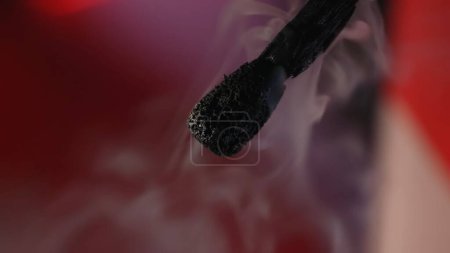 Photo for Macro shot of a black charred match and clouds of white smoke. Burned extinguished wooden match on studio background - Royalty Free Image