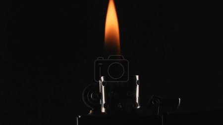 Téléchargez les photos : Le moment de l'allumage et de la combustion d'un briquet à essence est capturé sur un fond noir. Flamme lumineuse et dynamique du briquet dans un plan macro, créant un effet visuel passionnant - en image libre de droit