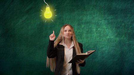 Photo for Imagination in problem solving concept. Portrait of woman isolated on green background light bulbs image on top. Girl standing reading book having idea raising finger up and lamp lights up - Royalty Free Image