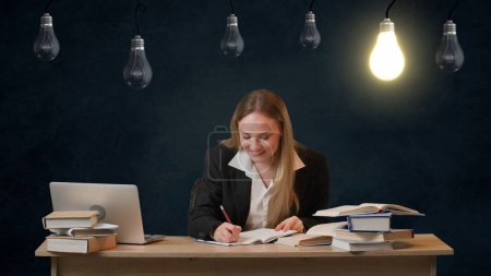 Photo for Imagination in problem solving creative concept. Portrait of girl on isolated background light bulbs hanging on top. Girl works on laptop, thinking finding idea and writes in notebook, lamp lights up. - Royalty Free Image