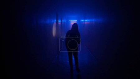 Téléchargez les photos : Lieux abandonnés et bâtiments vides concept publicitaire créatif. Portrait de femme dans le couloir sombre avec lumière au néon. Femme avec lampe de poche marchant dans le couloir avec porte et escalier. - en image libre de droit