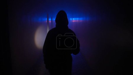 Photo for Abandoned places and empty buildings creative advertisement concept. Portrait of person in the hallway with neon light. Person in chemical protection suit with flashlight walking down the corridor. - Royalty Free Image
