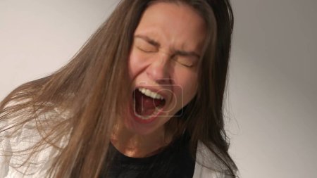 Photo for Human extreme emotions creative advertisement concept. Portrait of attractive female model in negative mood. Studio shot of brunette woman in hysterical mood, yelling screaming holding hands up. - Royalty Free Image