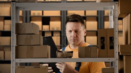 Photo for Business warehouse and logistics creative advertisement concept. Portrait of male working in storage. Man storekeeper near rack checking packages with paper documents , finding destroyed box on shelf. - Royalty Free Image