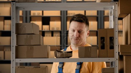 Photo for Business warehouse and logistics creative advertisement concept. Portrait of male working in storage. Man storekeeper near rack checking packages with paper documents , finding destroyed box on shelf. - Royalty Free Image