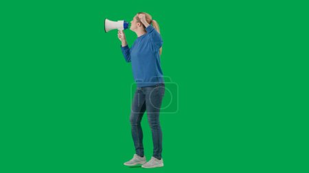 Téléchargez les photos : Militante au poing levé parlant menaçant en mégaphone en studio sur écran vert. Manifestation, lutte pour les droits des femmes, grève. Publicité, promo, clé chromatique - en image libre de droit