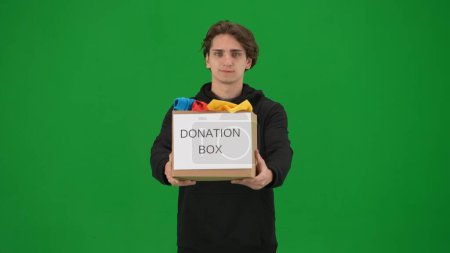 Photo for A man volunteer holds a box full of clothes labeled Donation box, close up. The man holds out the box. Concept of social assistance, volunteering, humanitarian and charity. Helping people - Royalty Free Image