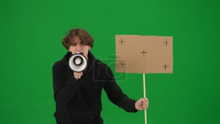 Photo for Man speaking into a megaphone and holds a blank placard in his hand. A man with a mouthpiece and placard on a green screen close up. Protest action, fight for human rights, strike. Advertising, promo - Royalty Free Image