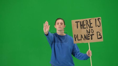 Photo for A young female activist shows a sign that says There is no planet B and makes a stop gesture with one hand. A woman in the studio on a green screen close up. Save the planet, global warming and - Royalty Free Image