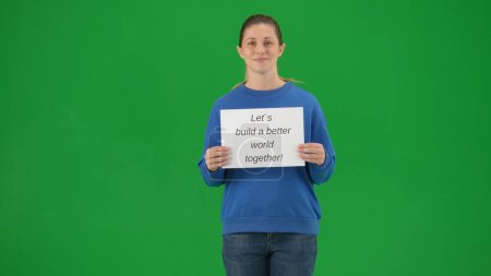 Téléchargez les photos : Une jeune militante tient une affiche qui dit : "Construisons un monde meilleur ensemble. Portrait d'une manifestante tenant une boîte de dons sur un écran vert gros plan - en image libre de droit