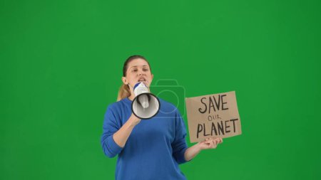 Foto de Una mujer habla en un megáfono y sostiene una pancarta que dice "Salve Nuestro Planeta". Mujer con una boquilla y un póster en una pantalla verde de cerca. Salvar el planeta, concepto de cambio climático, ecología - Imagen libre de derechos