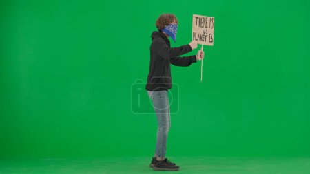 Téléchargez les photos : Une vue de côté d'un activiste masculin tenant une pancarte disant qu'il n'y a pas de planète B. Un manifestant masculin avec une pancarte sur un écran vert. Sauver la planète, le réchauffement climatique et le changement climatique - en image libre de droit