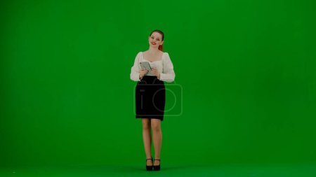 Téléchargez les photos : Femme d'affaires moderne concept de publicité créative. Portrait d'une jolie fille de bureau sur écran vert chroma. Femme en jupe et chemisier tenant tablette, service de publicité. - en image libre de droit