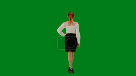 Téléchargez les photos : Femme d'affaires moderne concept de publicité créative. Portrait d'une jolie fille de bureau sur écran vert chroma. Femme en jupe et chemisier marchant mignonne. Vue arrière. - en image libre de droit
