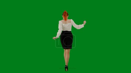 Téléchargez les photos : Femme d'affaires moderne concept de publicité créative. Portrait d'une jolie fille de bureau sur écran vert chroma. Femme en jupe et chemisier marchant mignonne. Vue arrière. - en image libre de droit