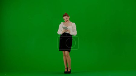 Téléchargez les photos : Femme d'affaires moderne concept de publicité créative. Portrait d'une jolie fille de bureau sur écran vert chroma. Femme en jupe et chemisier tenant tablette, service de publicité. - en image libre de droit