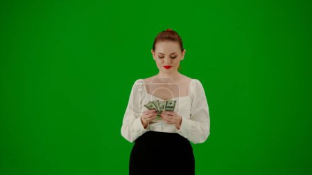 Photo for Modern business woman creative advertisement concept. Portrait of attractive office girl on chroma key green screen. Woman in skirt and blouse walking and counting money, happy face expression. - Royalty Free Image