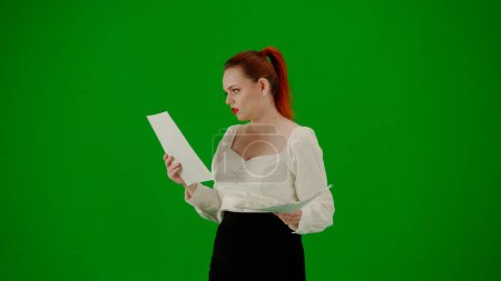 Foto de Mujer de negocios moderna. Retrato de atractiva chica de oficina en croma pantalla verde clave. Mujer en falda y blusa caminando leyendo documentos en papel, expresión facial enfocada. Media vuelta.. - Imagen libre de derechos