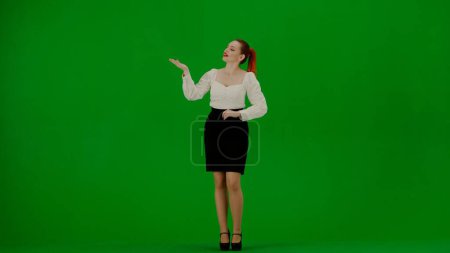 Photo for Modern business woman creative advertisement concept. Portrait of attractive office girl on chroma key green screen. Woman in skirt and blouse standing pointing at empty areas smiling at camera. - Royalty Free Image