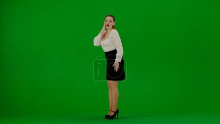 Foto de Mujer de negocios moderna concepto de publicidad creativa. Retrato de atractiva chica de oficina en croma pantalla verde clave. Mujer en falda y blusa posando con expresión de cara sorprendida, ganando gesto. - Imagen libre de derechos