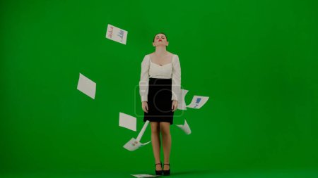 Foto de Mujer de negocios moderna concepto de publicidad creativa. Retrato de atractiva chica de oficina en croma pantalla verde clave. Mujer en falda y blusa sosteniendo papeles, frustrado arrojando documentos en el aire. - Imagen libre de derechos