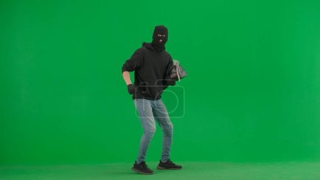 Foto de Robo y concepto criminal. Retrato de ladrón en croma pantalla verde clave de fondo. Hombre ladrón con bolsa robada. - Imagen libre de derechos